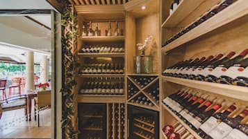A wine cellar with wooden shelves and racks, and a glass display case with wine bottles.