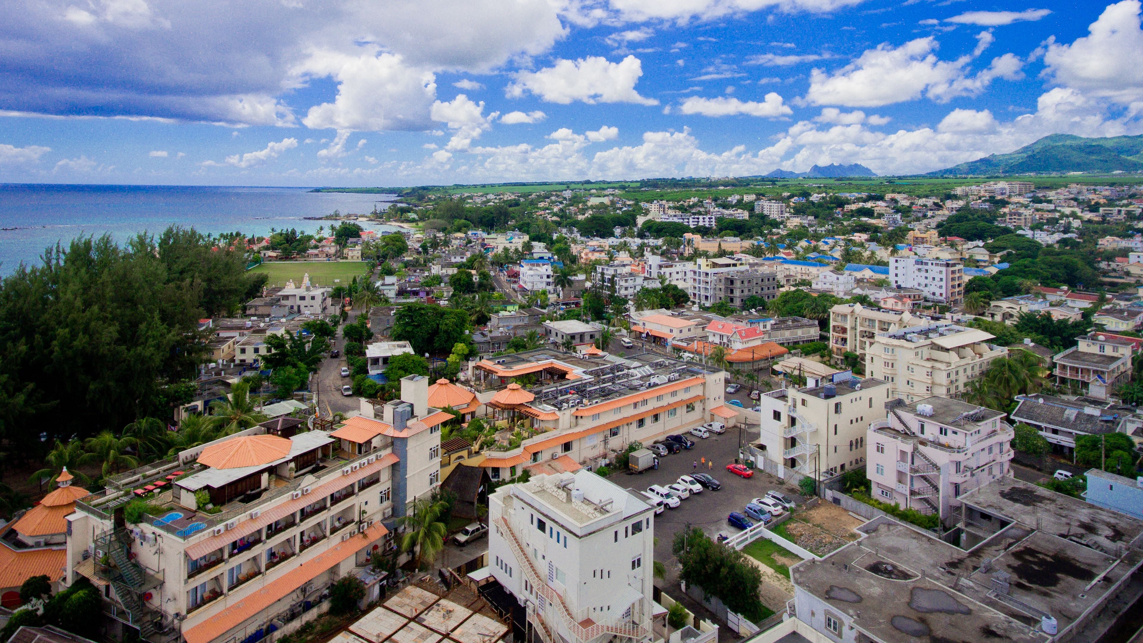 Paisagem costeira com uma mistura de edifícios residenciais e comerciais, incluindo estruturas com vários andares, varandas e telhados planos.
