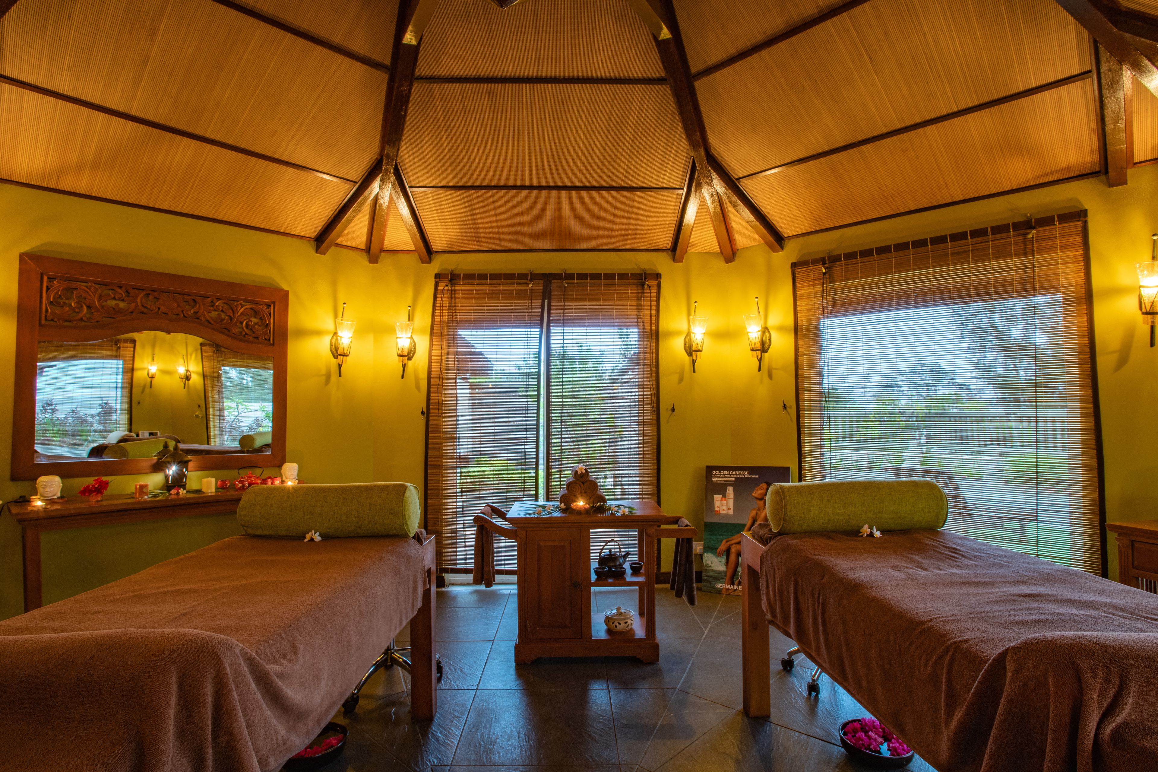 A room with two beds, a wooden table, and a mirror.