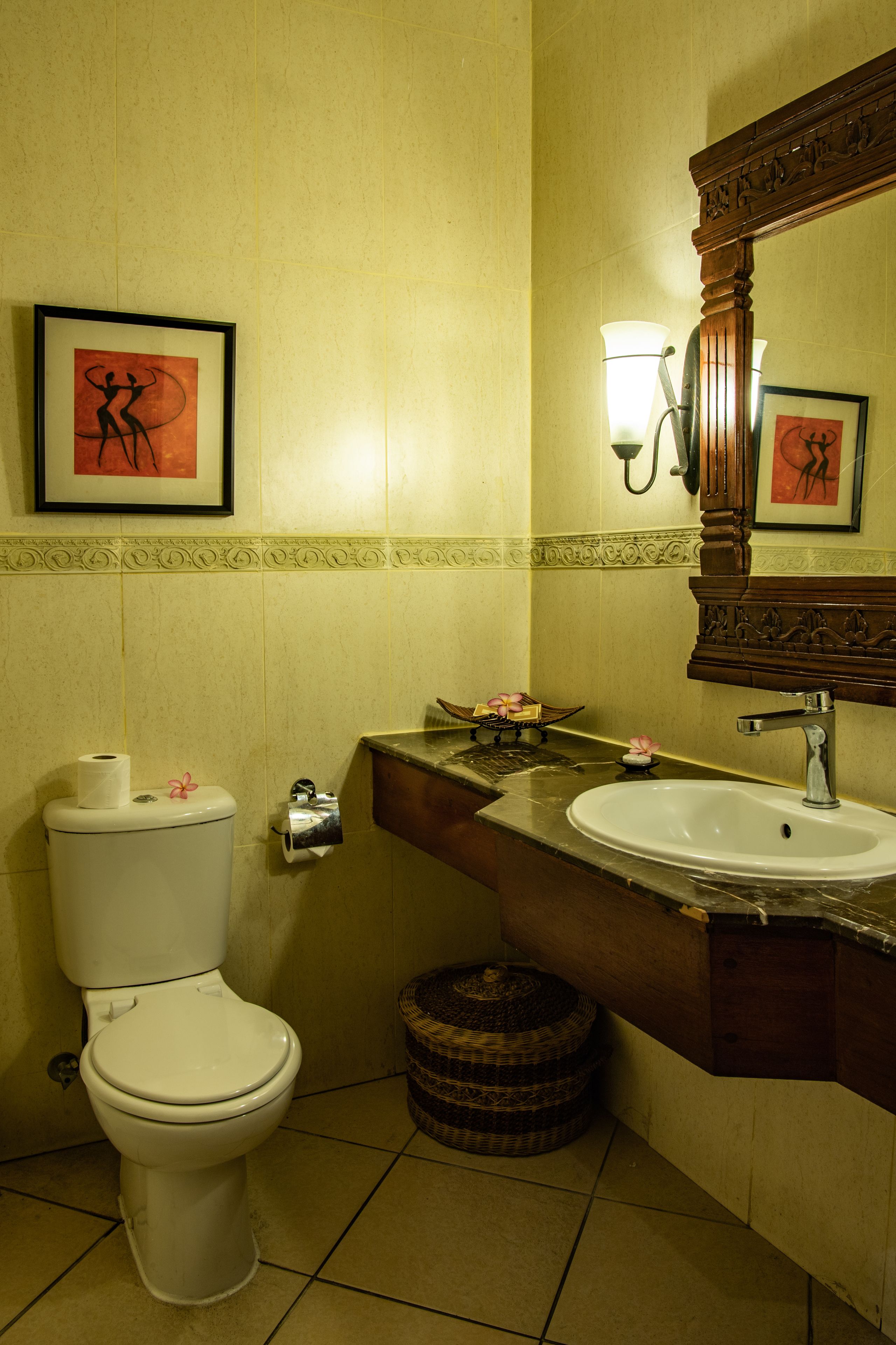A bathroom with a toilet, sink, and decorative items on the counter.