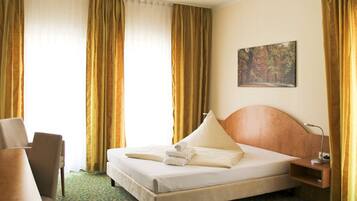 Ein Hotelzimmer mit Bett, Stuhl, Schreibtisch und einem Bild an der Wand.