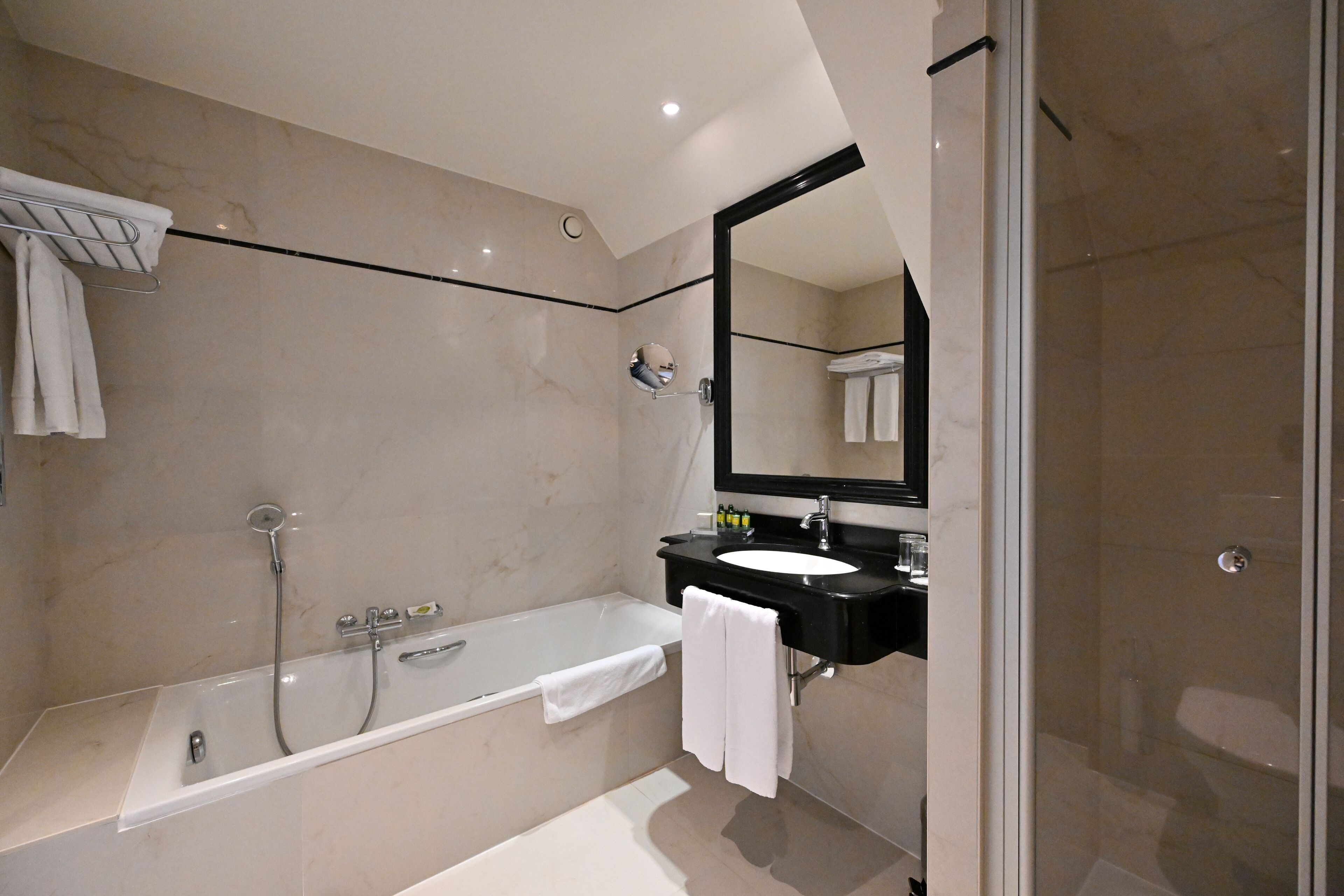 Un baño moderno con bañera, lavamanos y un espejo grande.