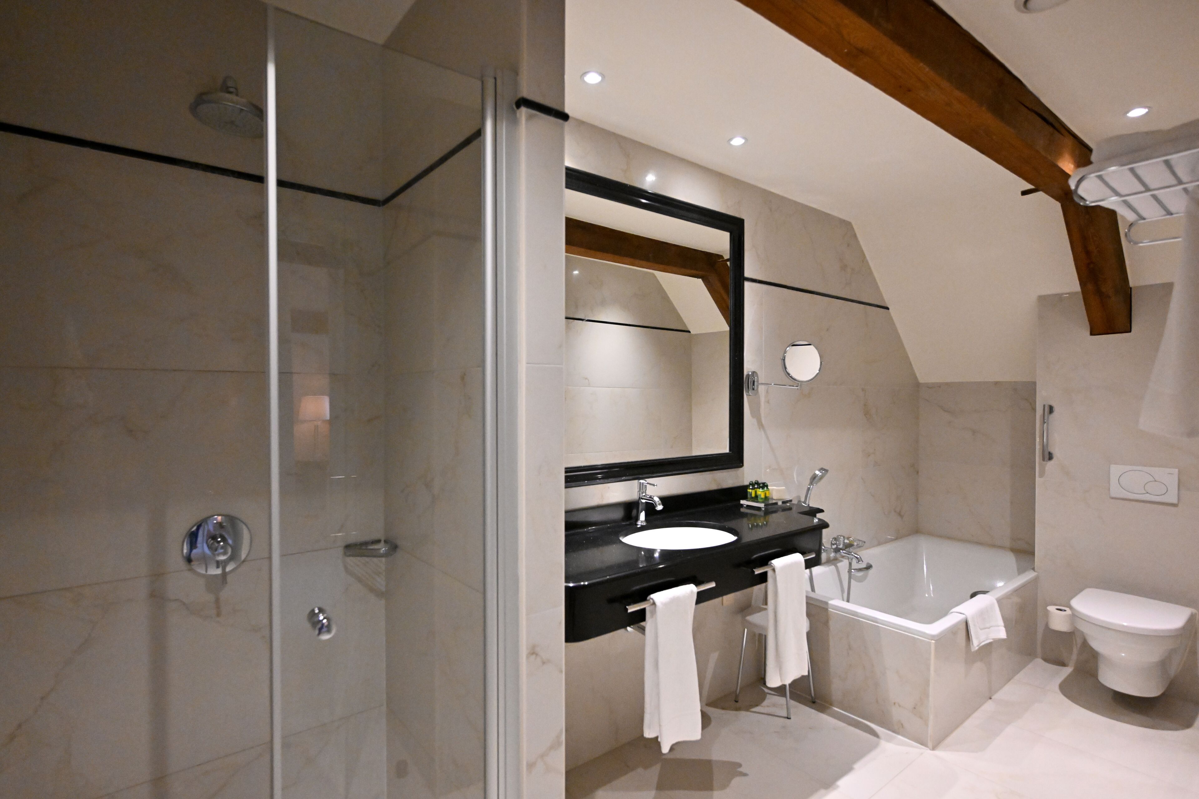 A modern bathroom with a glass-enclosed shower, a black sink, a large mirror, and a freestanding bathtub.