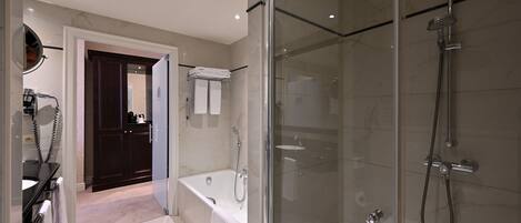 Un baño moderno con ducha envuelta en vidrio, una bañera independiente y un tocador con espejo y teléfono.