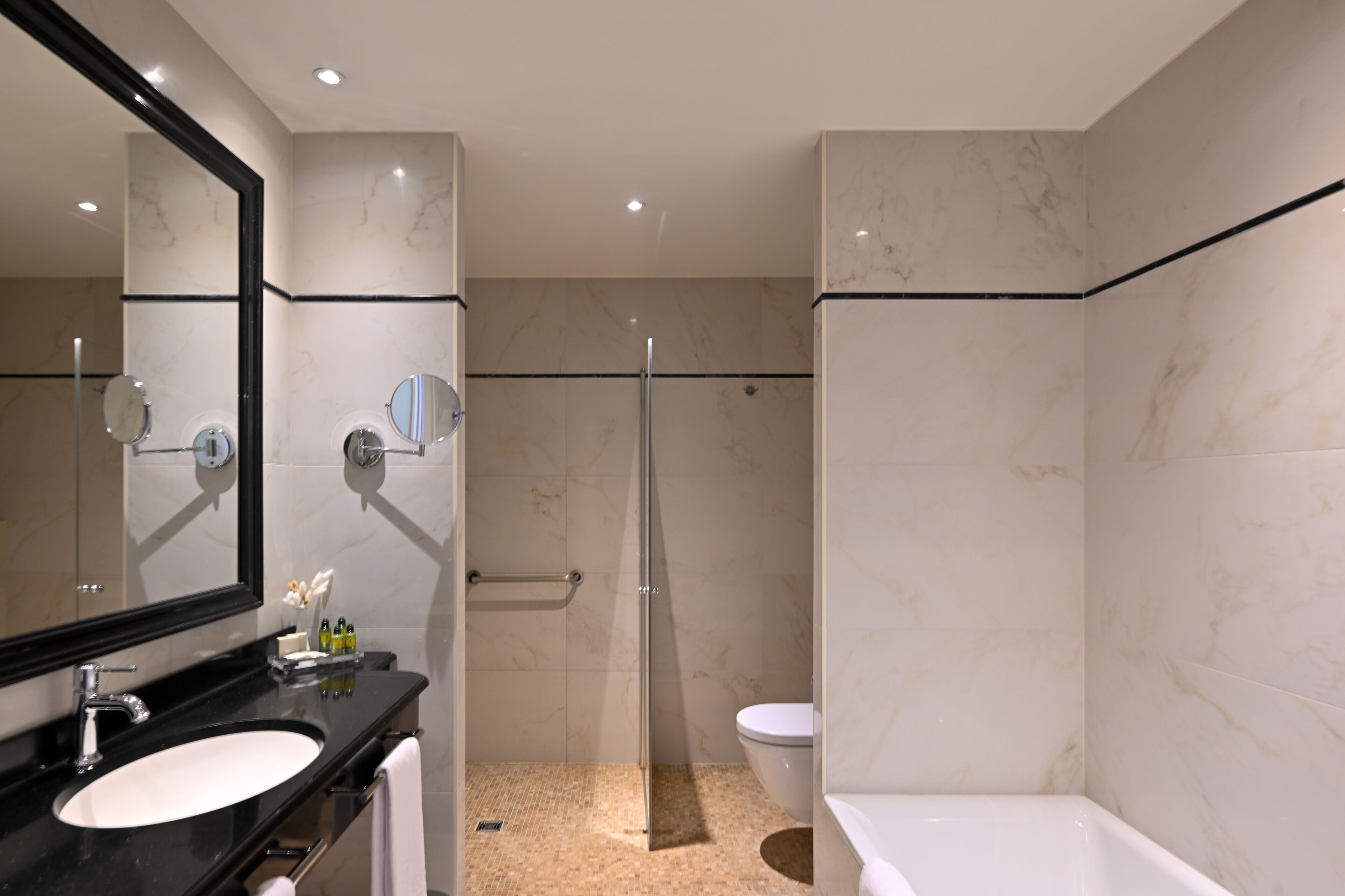 A modern bathroom with a large mirror, a sink, a toilet, and a shower area.