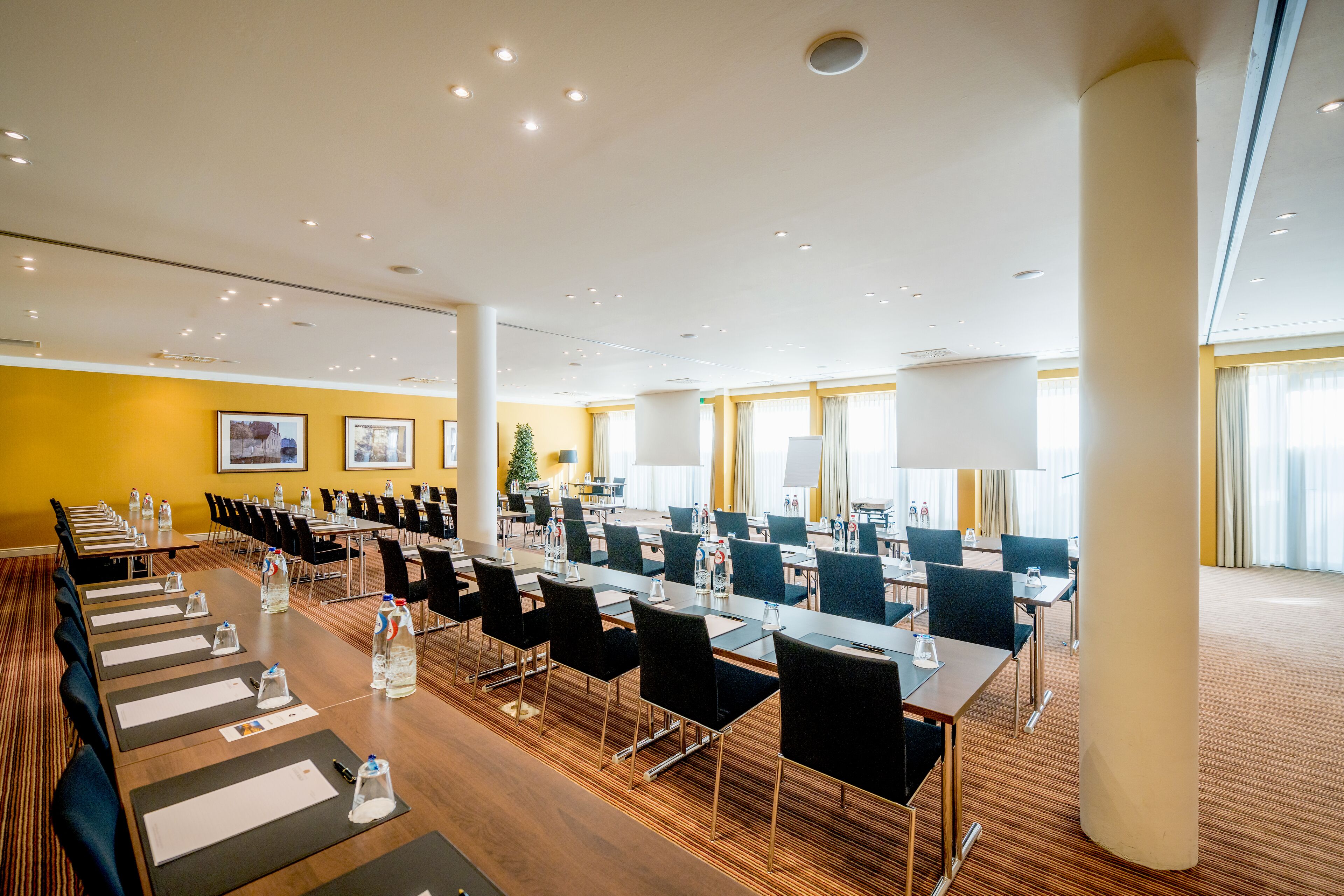 A conference room with long tables, chairs, and water bottles.