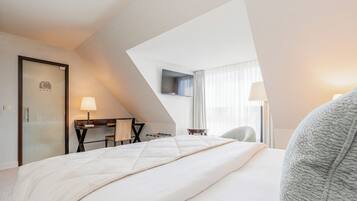 Une chambre d’hôtel avec un lit, un bureau, une chaise, une télévision et une fenêtre avec des rideaux.