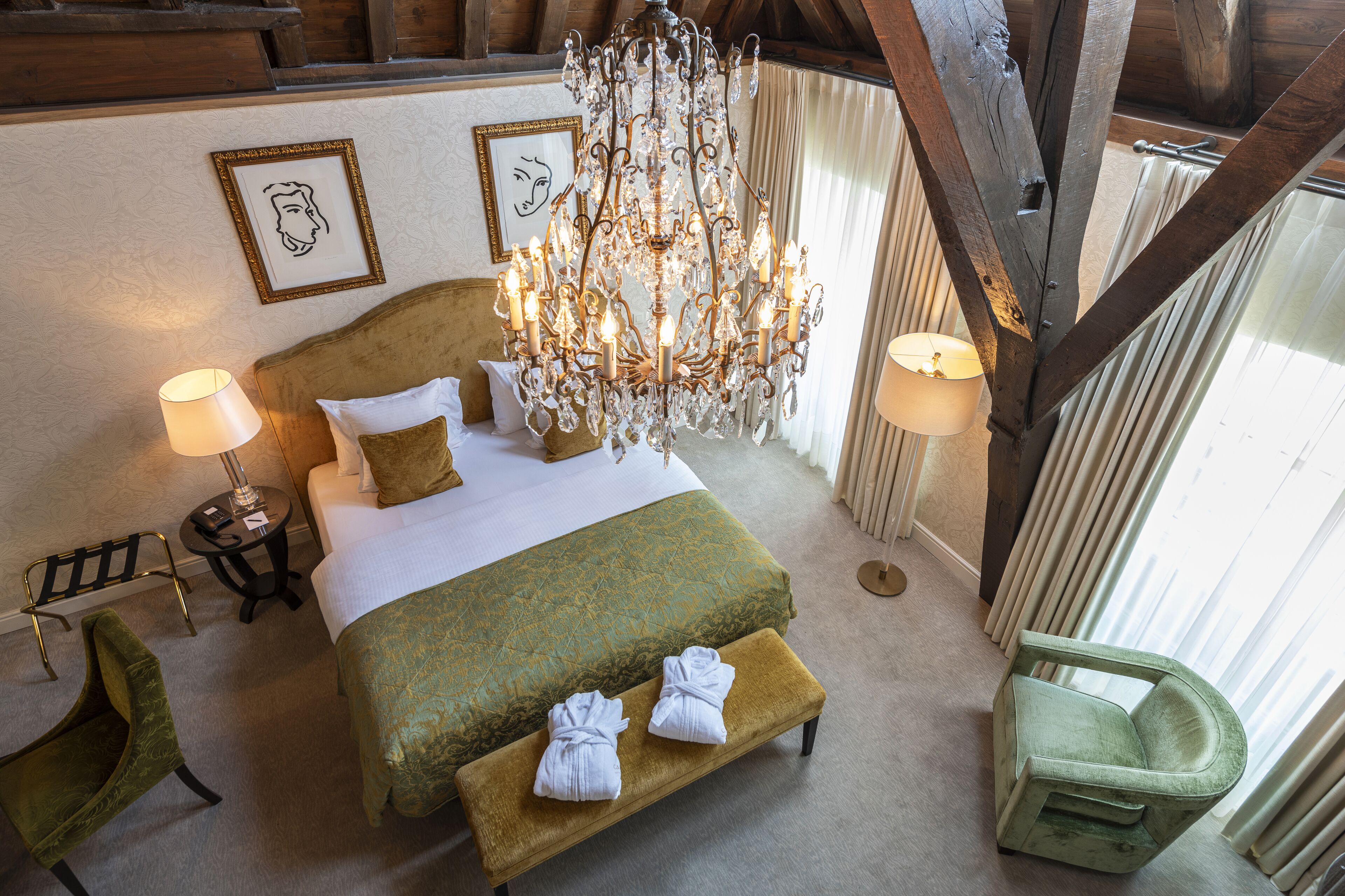 A spacious bedroom with a large bed, a chandelier, and a view of the outdoors.