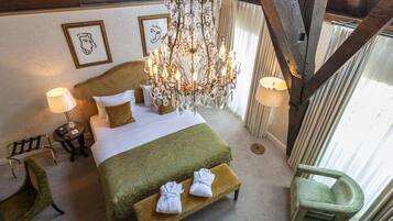 A spacious bedroom with a large bed, a chandelier, and a view of the outdoors.