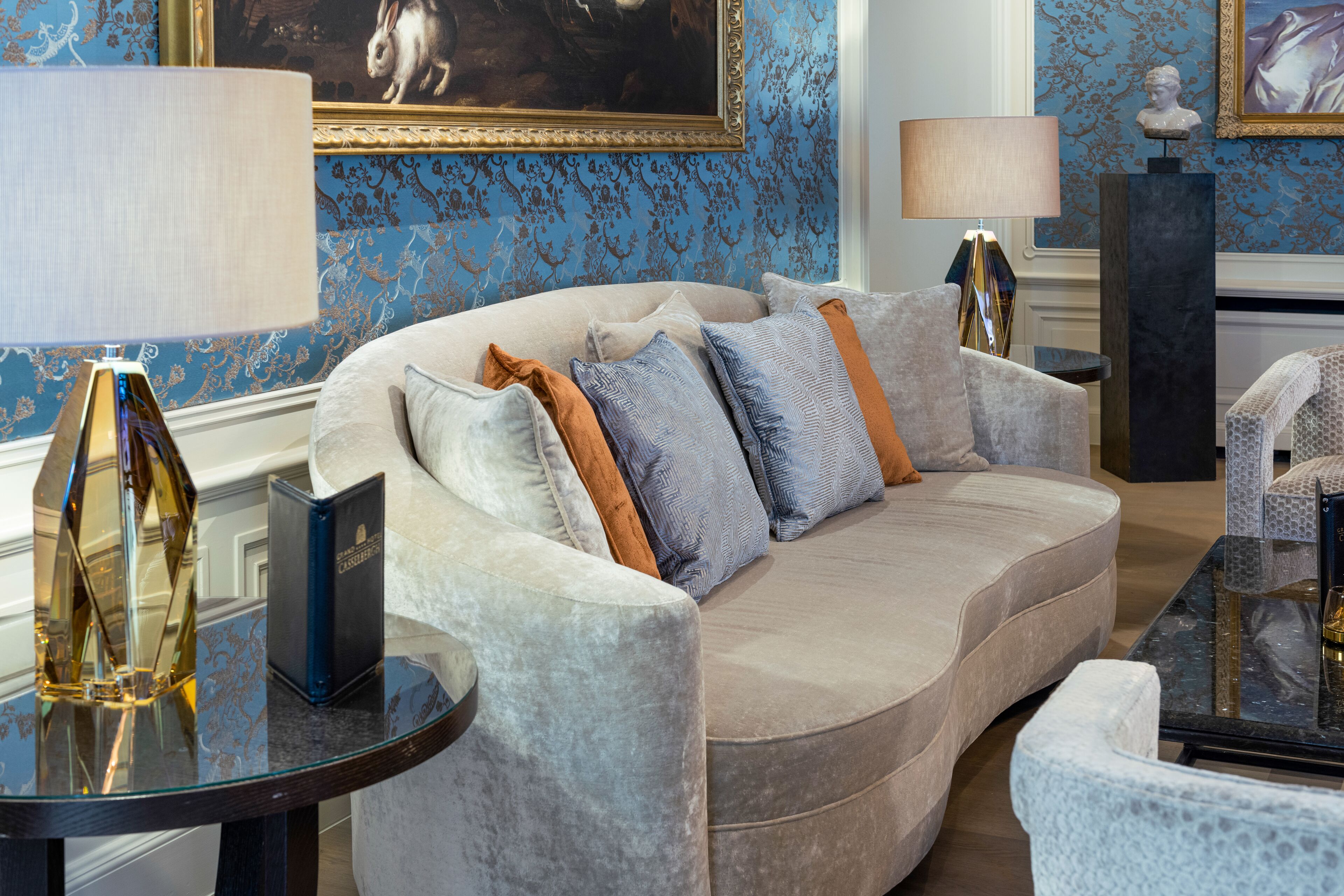 A plush sofa with multiple pillows, a glass coffee table, and a lamp.