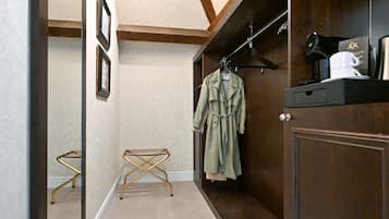 Un couloir avec une armoire en bois, un porte-manteau sur lequel est accroché un manteau vert, une machine à café et une petite table avec un pied doré.