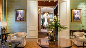 A formal lobby with patterned wallpaper, chandeliers, and framed portraits. - Grand Hotel Casselbergh Bruges (Bruges)