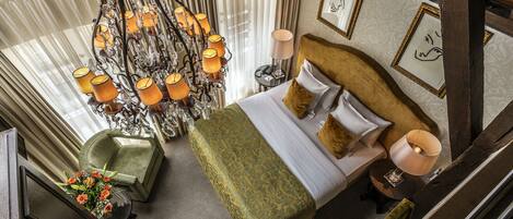 A high-ceilinged room with a large bed, a chandelier, and a view of the outdoors.