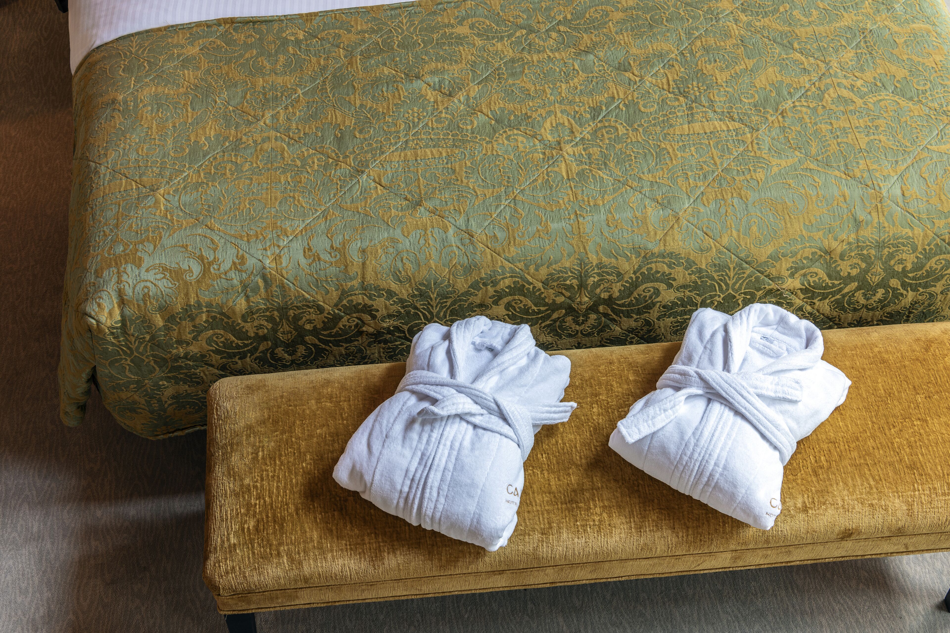 Un canapé de couleur dorée, recouvert d’un tissu à motifs, et deux serviettes blanches posées sur un banc en bois.