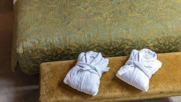 Un canapé de couleur dorée, recouvert d’un tissu à motifs, et deux serviettes blanches posées sur un banc en bois.