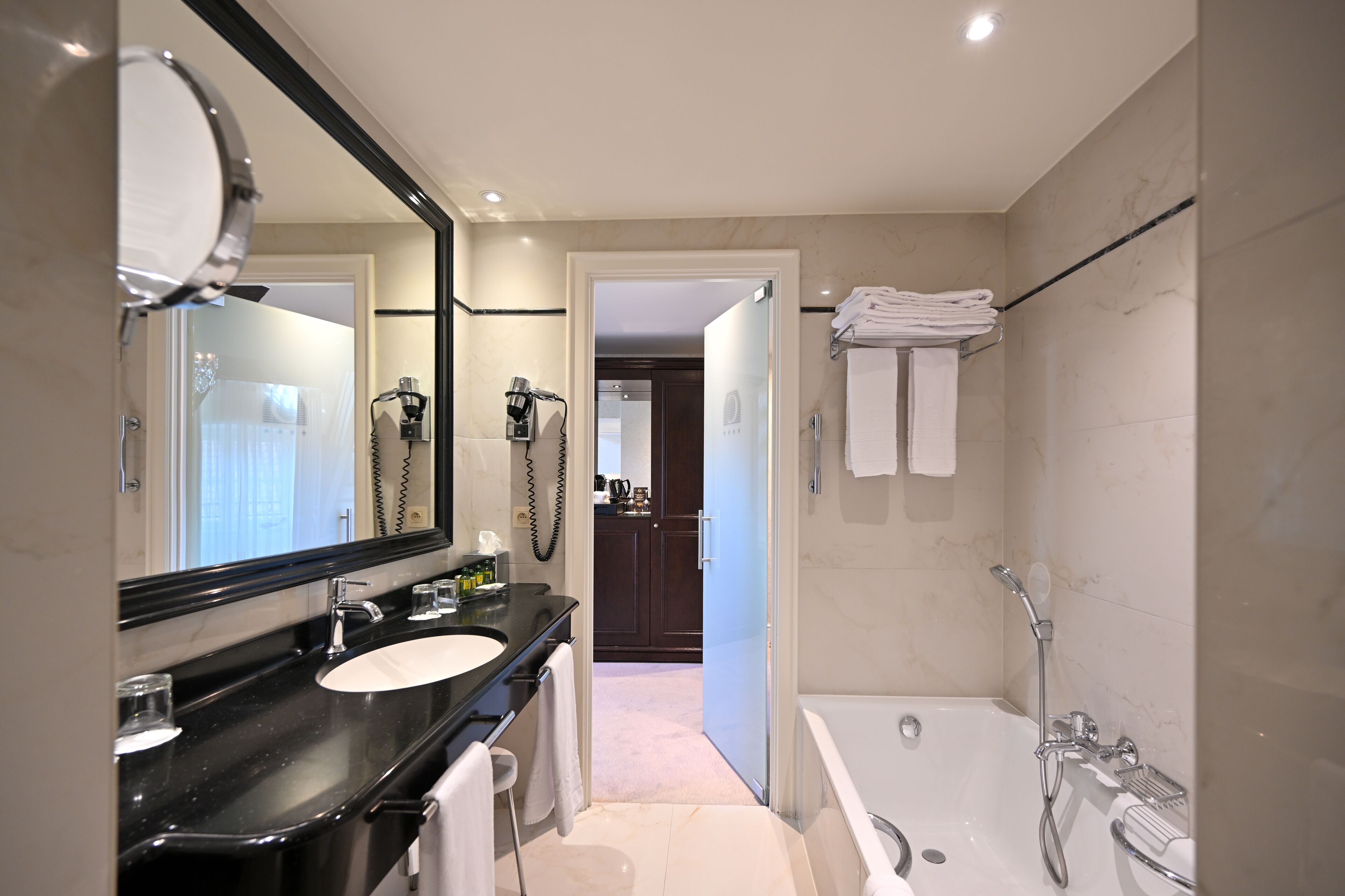 A modern bathroom with a black countertop sink, a large mirror, a bathtub, and a shower.