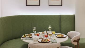 A dining area with a round table set for a meal, surrounded by green upholstered seating.