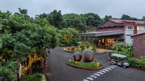 A hotel entrance with a paved driveway, a golf cart, and a landscaped garden with decorative spheres and string lights. - Fountain, Mahabaleshwar - IHCL SeleQtions (Mahabaleshwar)