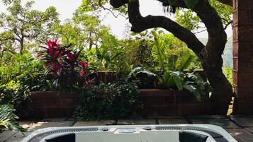 A hot tub surrounded by lush greenery and a brick wall.
