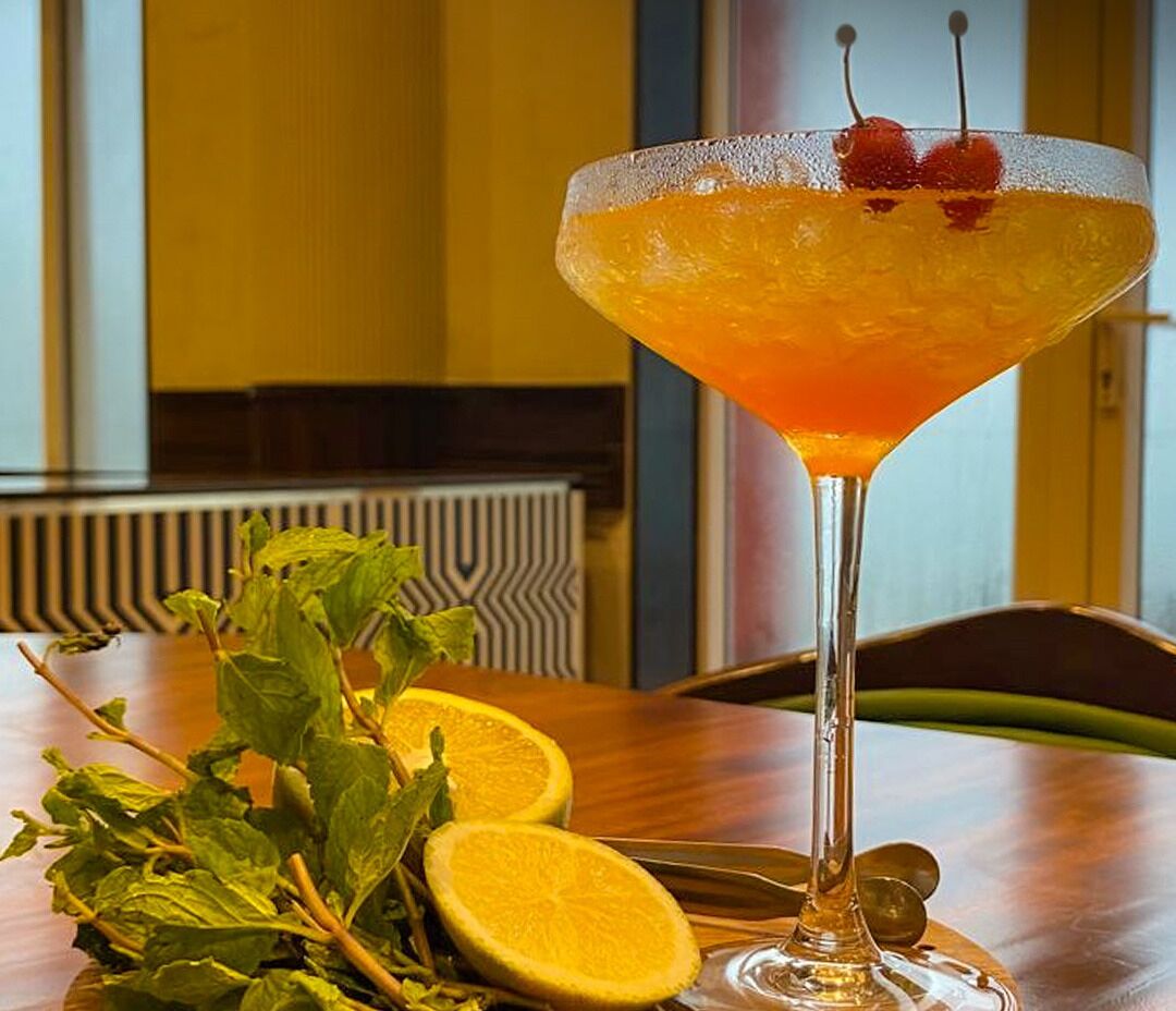 Una copa de martini con un adorno cítrico sobre una mesa de madera.