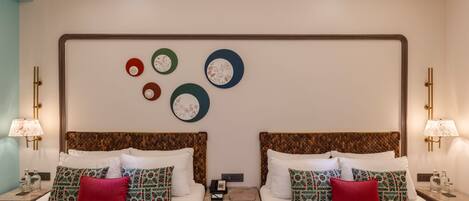 A hotel room with two beds, each with patterned pillows and a nightstand with a lamp and a phone.