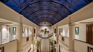 A spacious, well-lit atrium with a geometric patterned floor, a central staircase, and a high ceiling with a blue-tinted glass structure. - Fountain, Mahabaleshwar - IHCL SeleQtions (Mahabaleshwar)