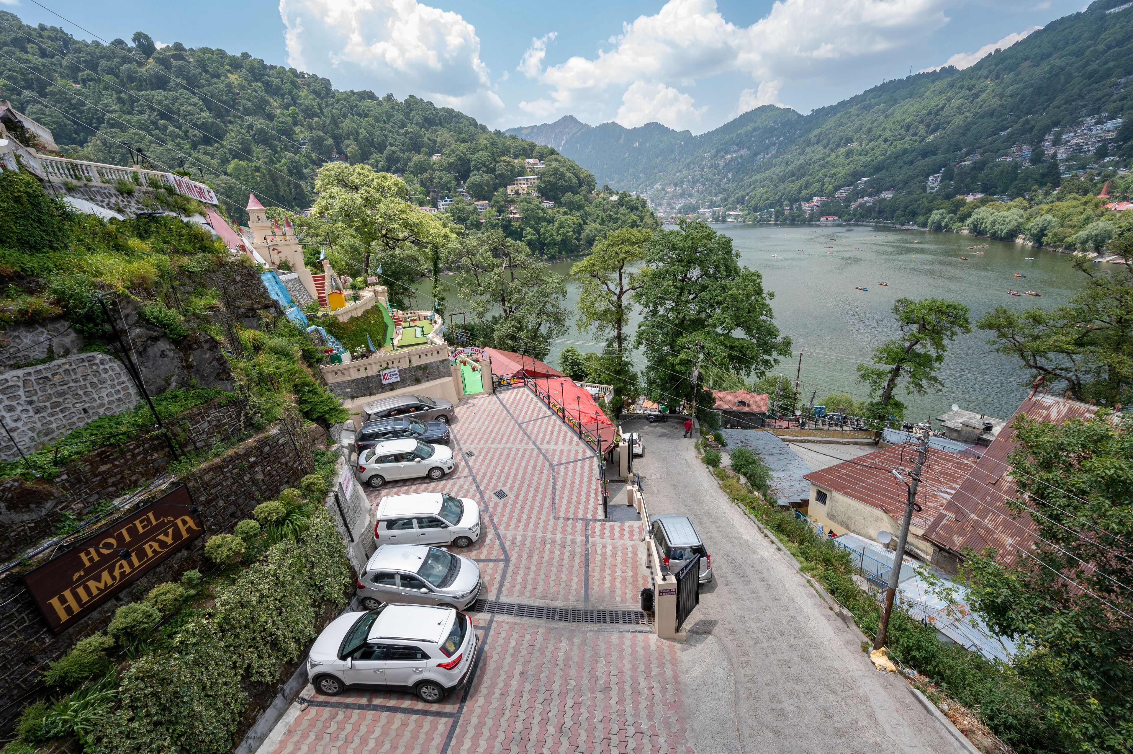 Un albergo con parcheggio pavimentato, vista sul fiume e montagne sullo sfondo.