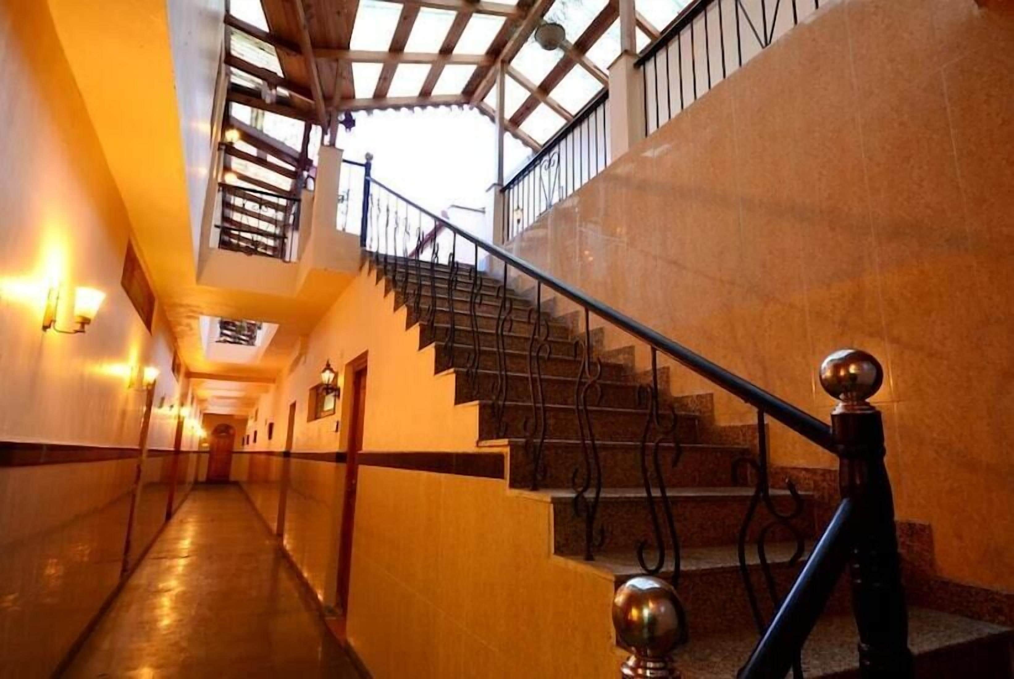 A corridor with a staircase leading to an upper level, featuring a skylight and a metal railing.