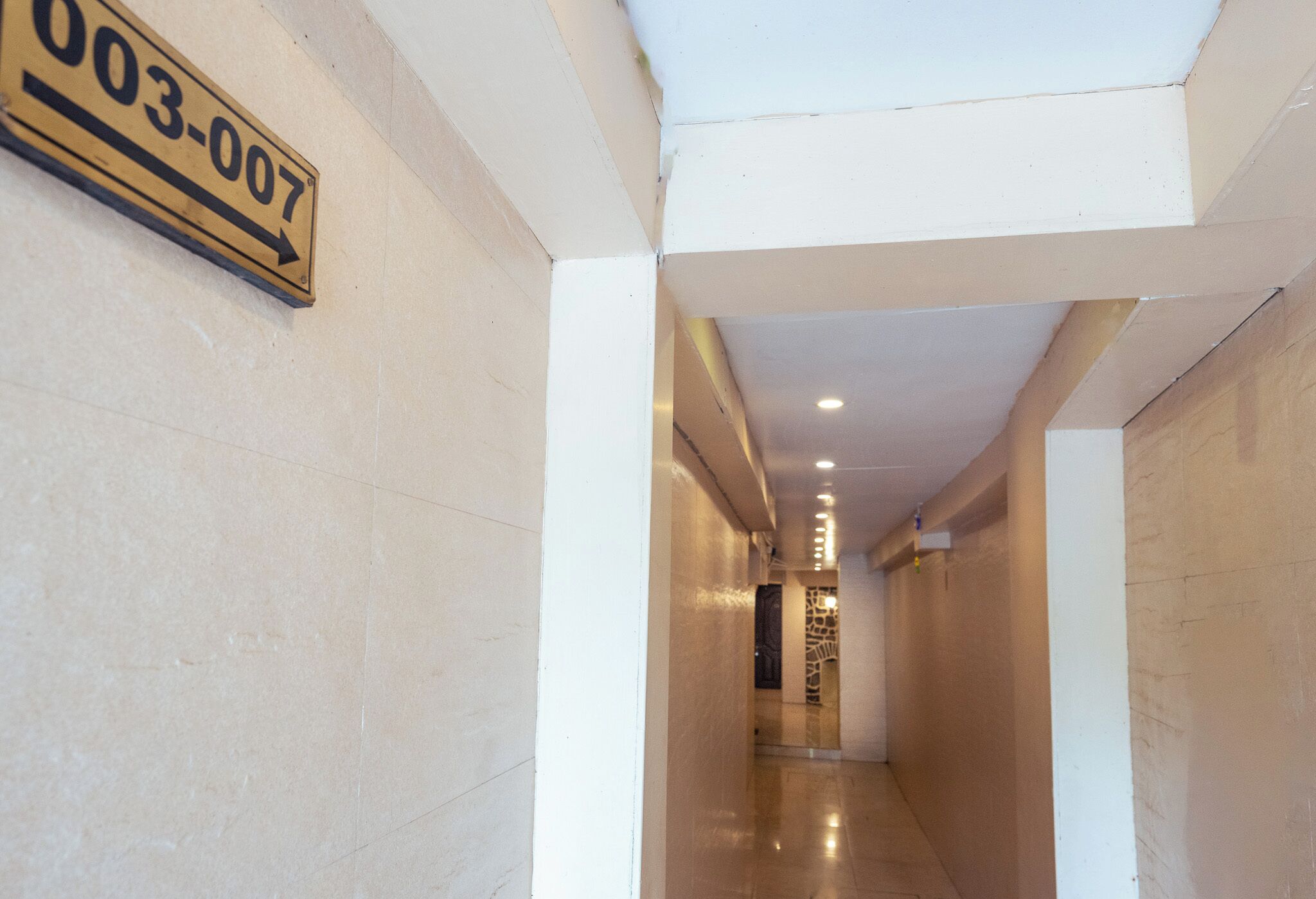 A hallway with a sign reading "003-007" and a stone wall at the end.