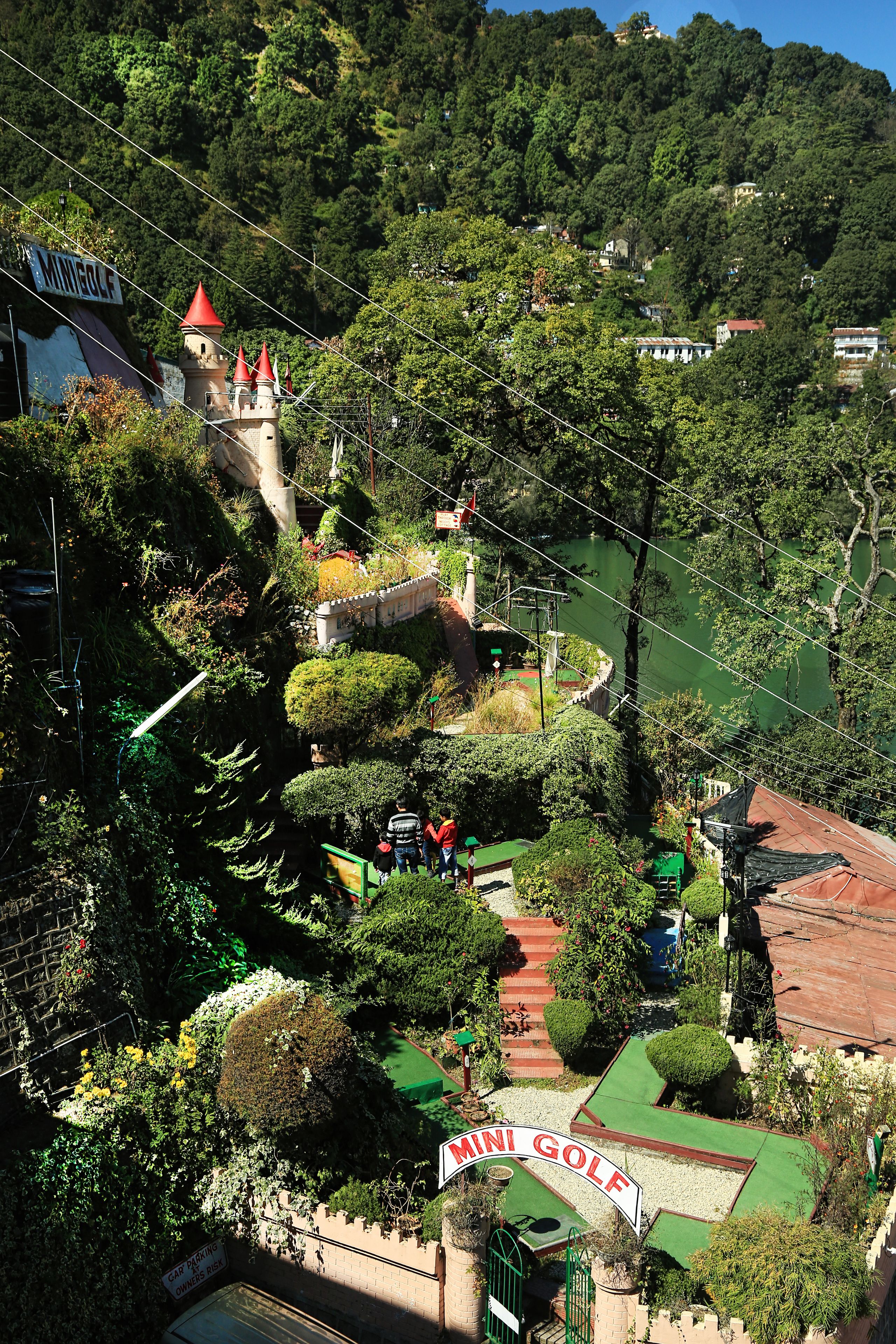 A mini-golf course surrounded by lush greenery and a castle-like structure.