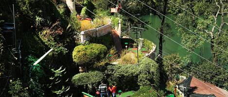 A mini-golf course surrounded by lush greenery and a castle-like structure.