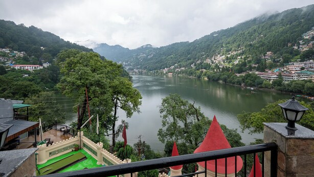 A view of a river valley with a castle-like structure in the foreground, surrounded by lush greenery and a mountainous backdrop. - Hotel Himalaya (Nainital)