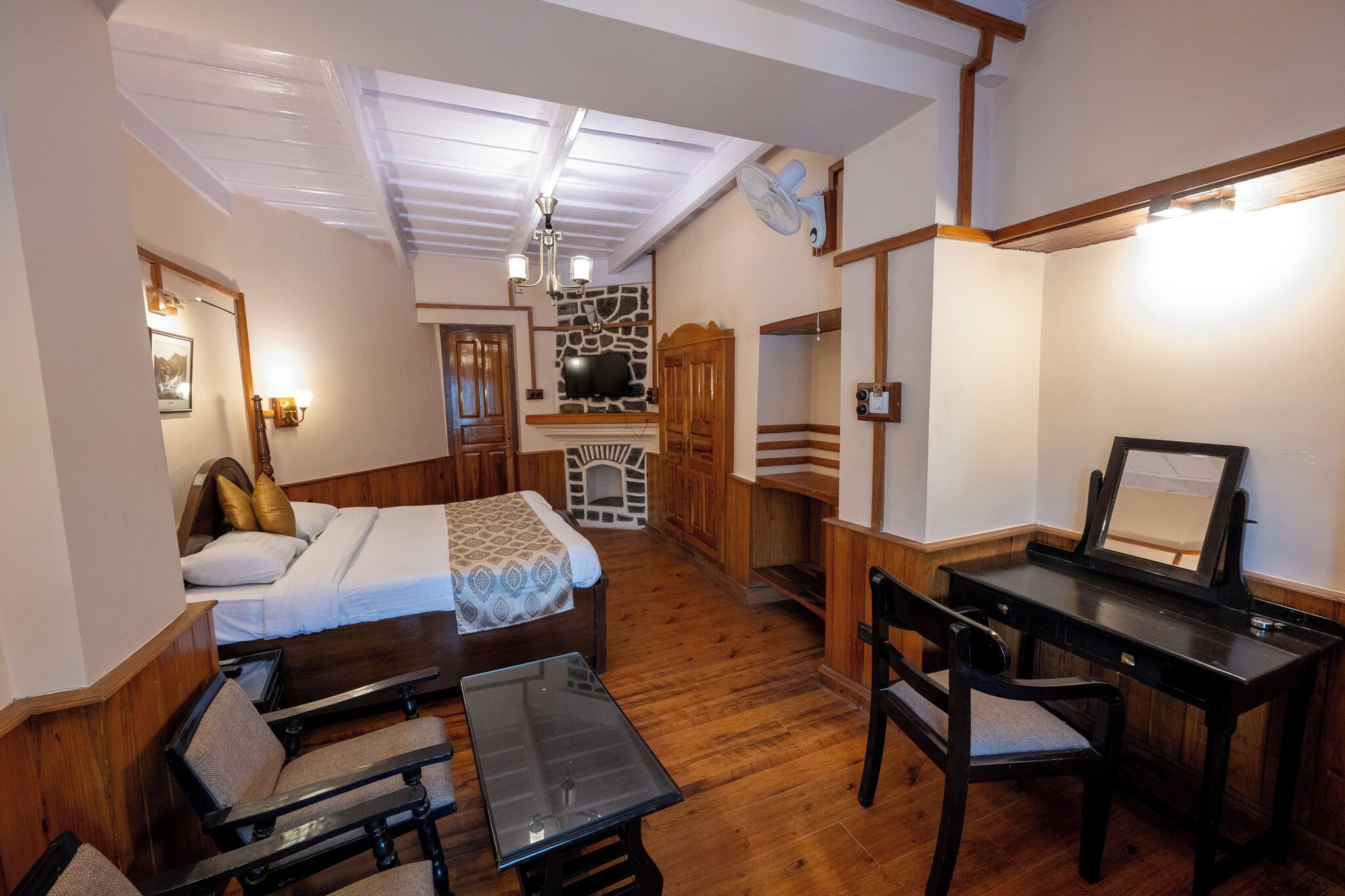 Quarto com cama, escrivaninha, cadeira, mesa e lareira.