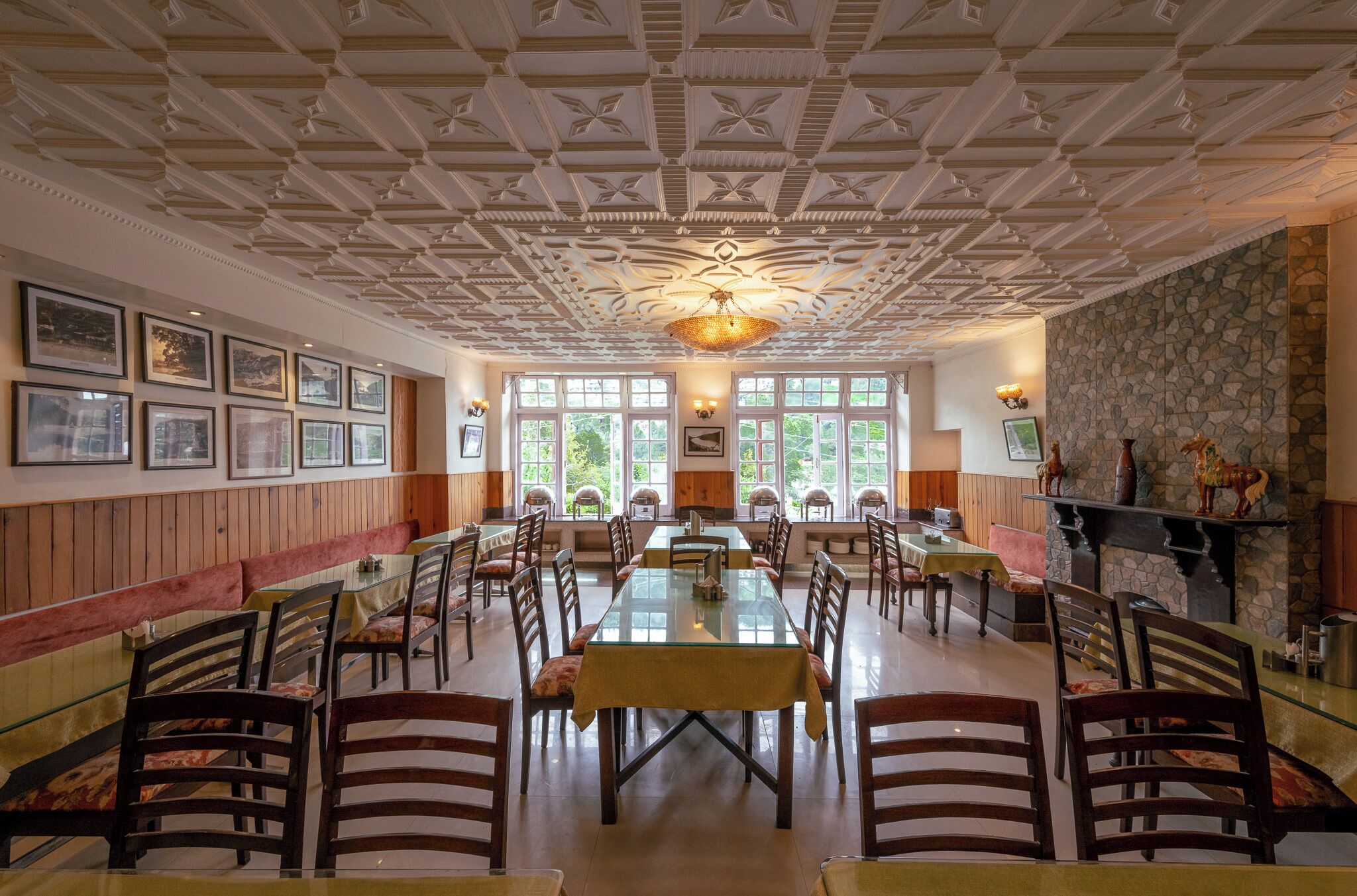 A spacious dining area with a high ceiling, large windows, and a stone fireplace.