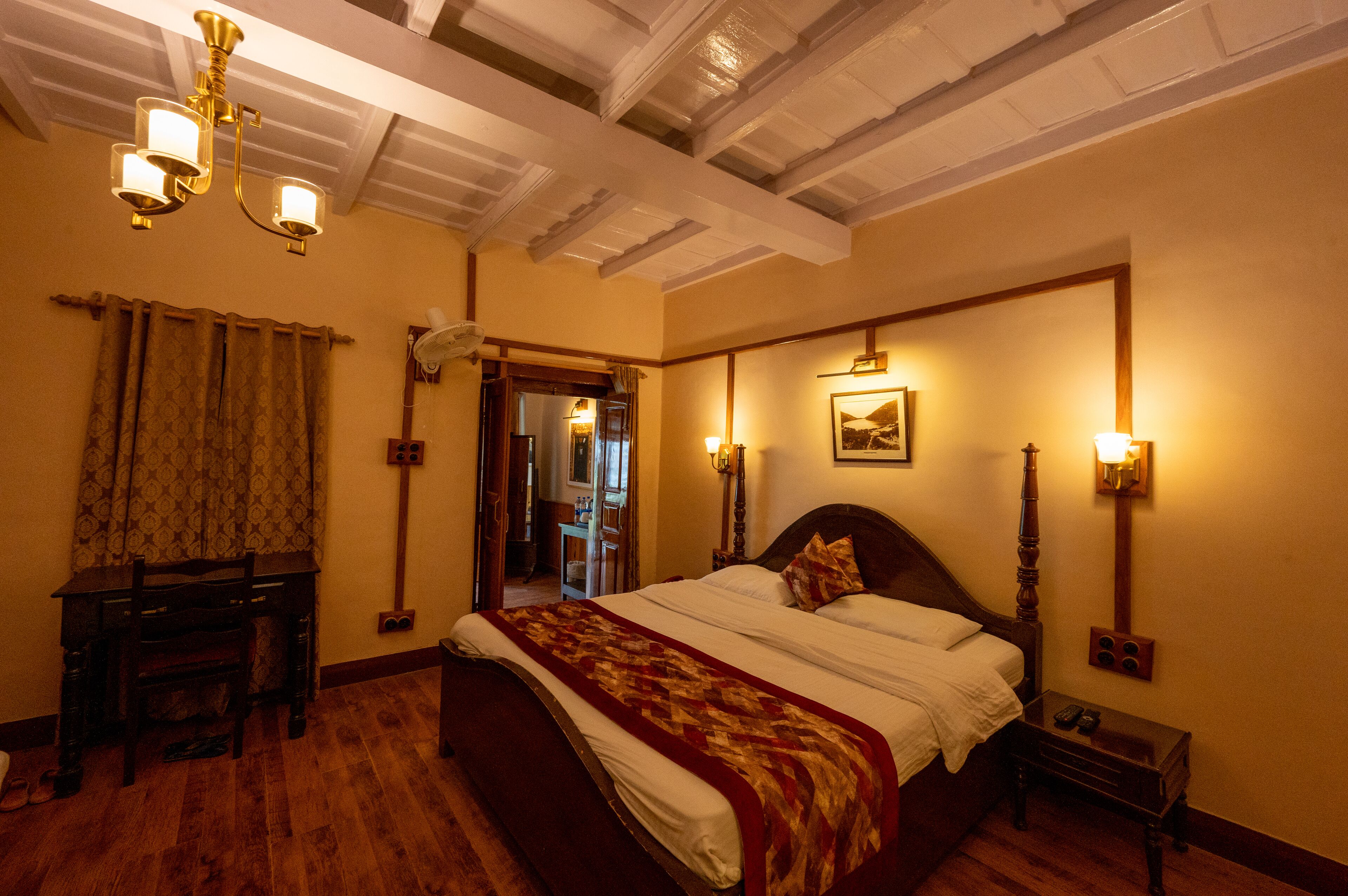 A hotel room with a large bed, wooden furniture, and a chandelier.
