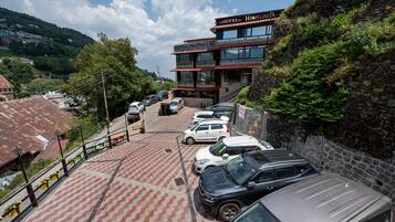 Ein mehrstöckiges Hotel mit einer Stein-Fassade und einem Parkplatz mit mehreren Autos.