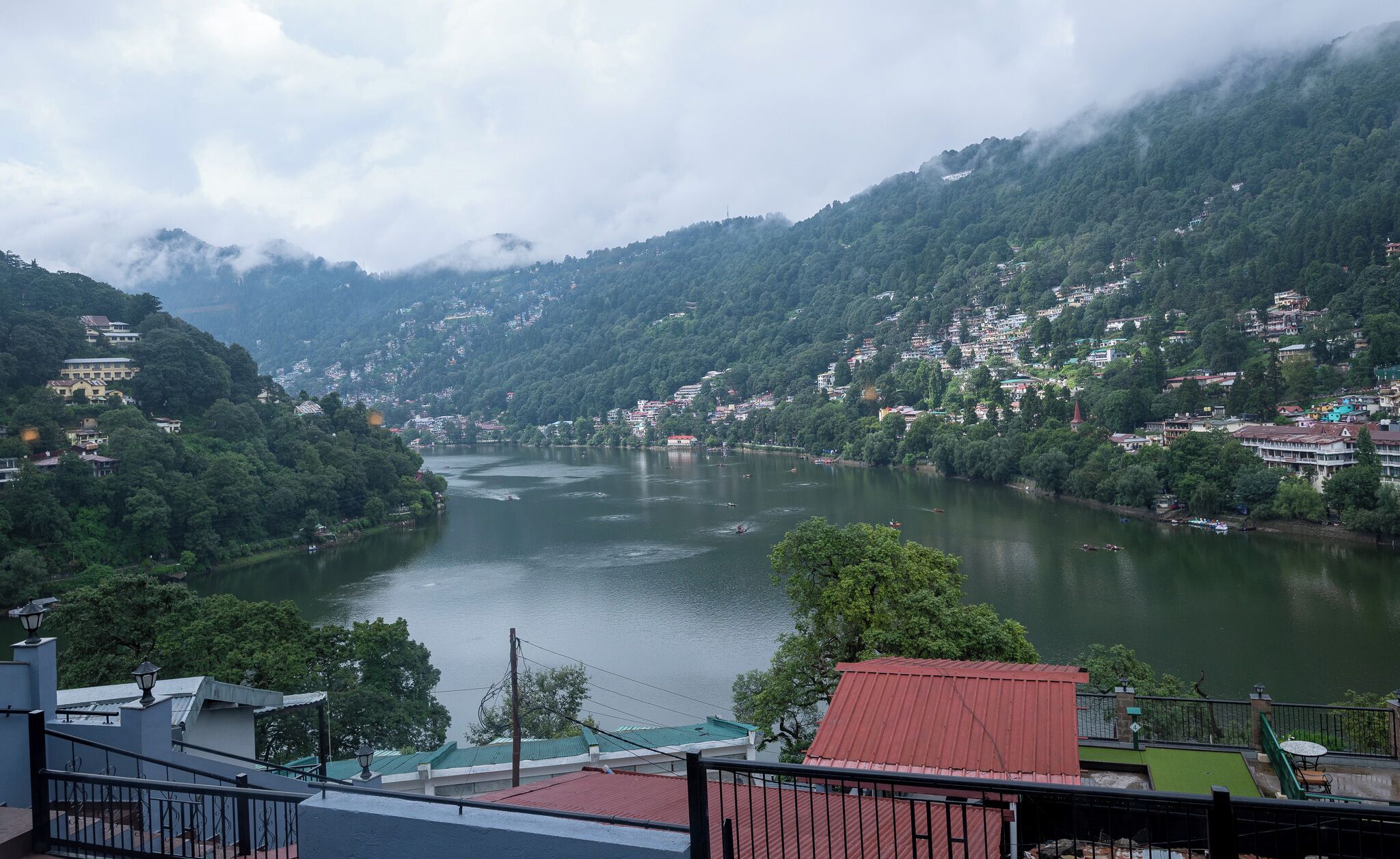 A river with buildings on both sides, surrounded by forested hills.
