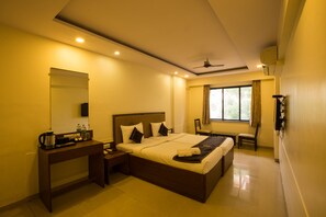 A hotel room with a large bed, bedside table, and a desk. - Ace Residency (Mumbai)