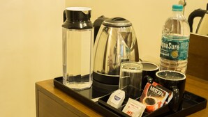 Una bandeja con una botella de agua, cafetera, taza y sobres de café.