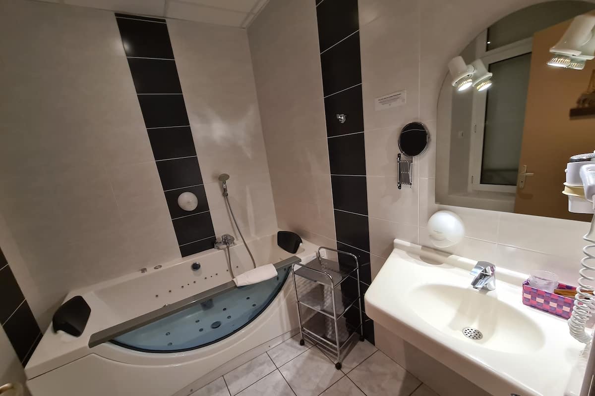 A bathroom with a bathtub, a sink, and a mirror.