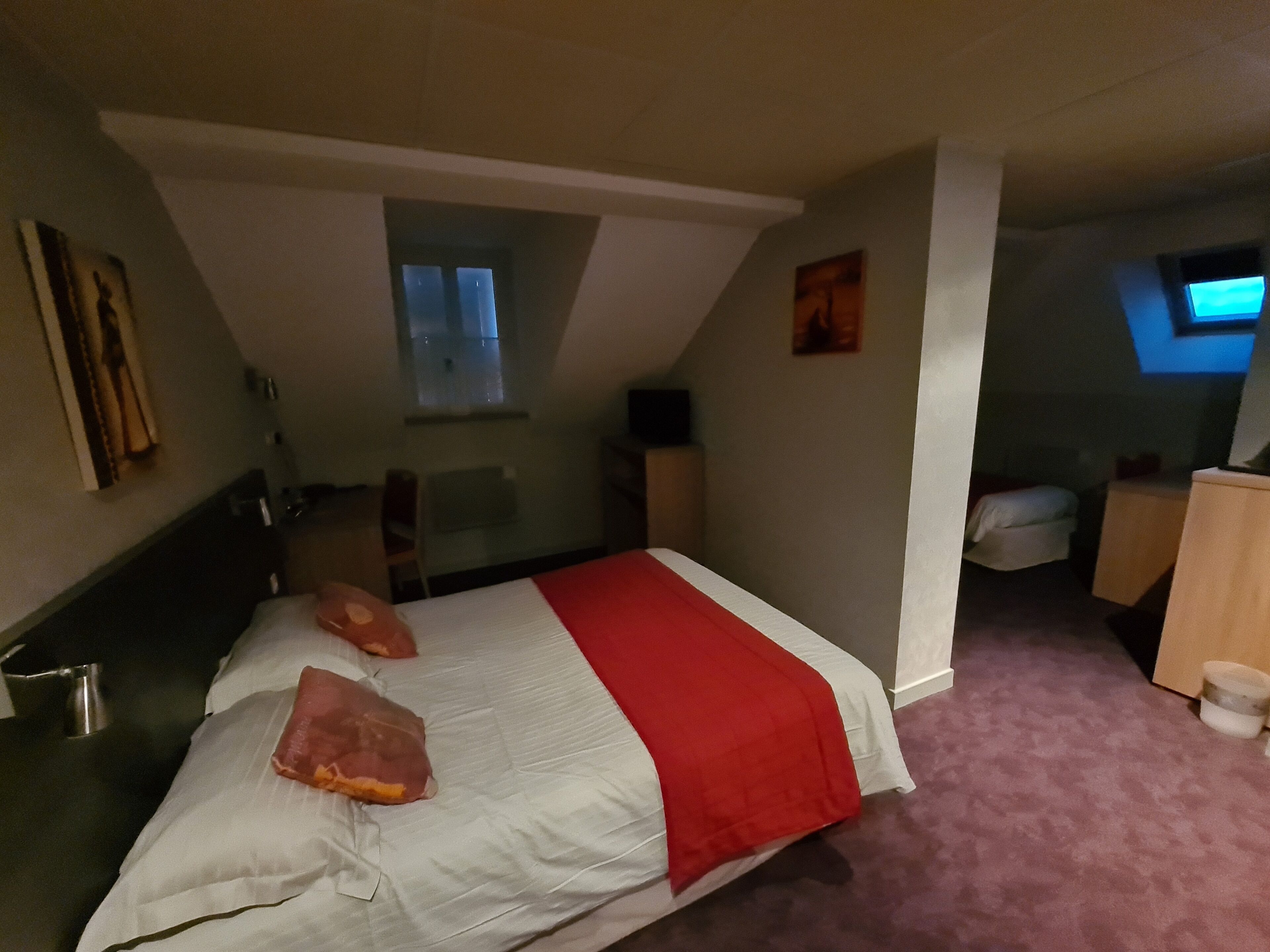 Un dormitorio con una cama, un escritorio pequeño, una silla, un televisor y una ventana.