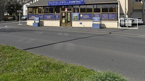 A building labeled "HOSTELLERIE du CANTAL" with a signboard and information displays at the entrance.