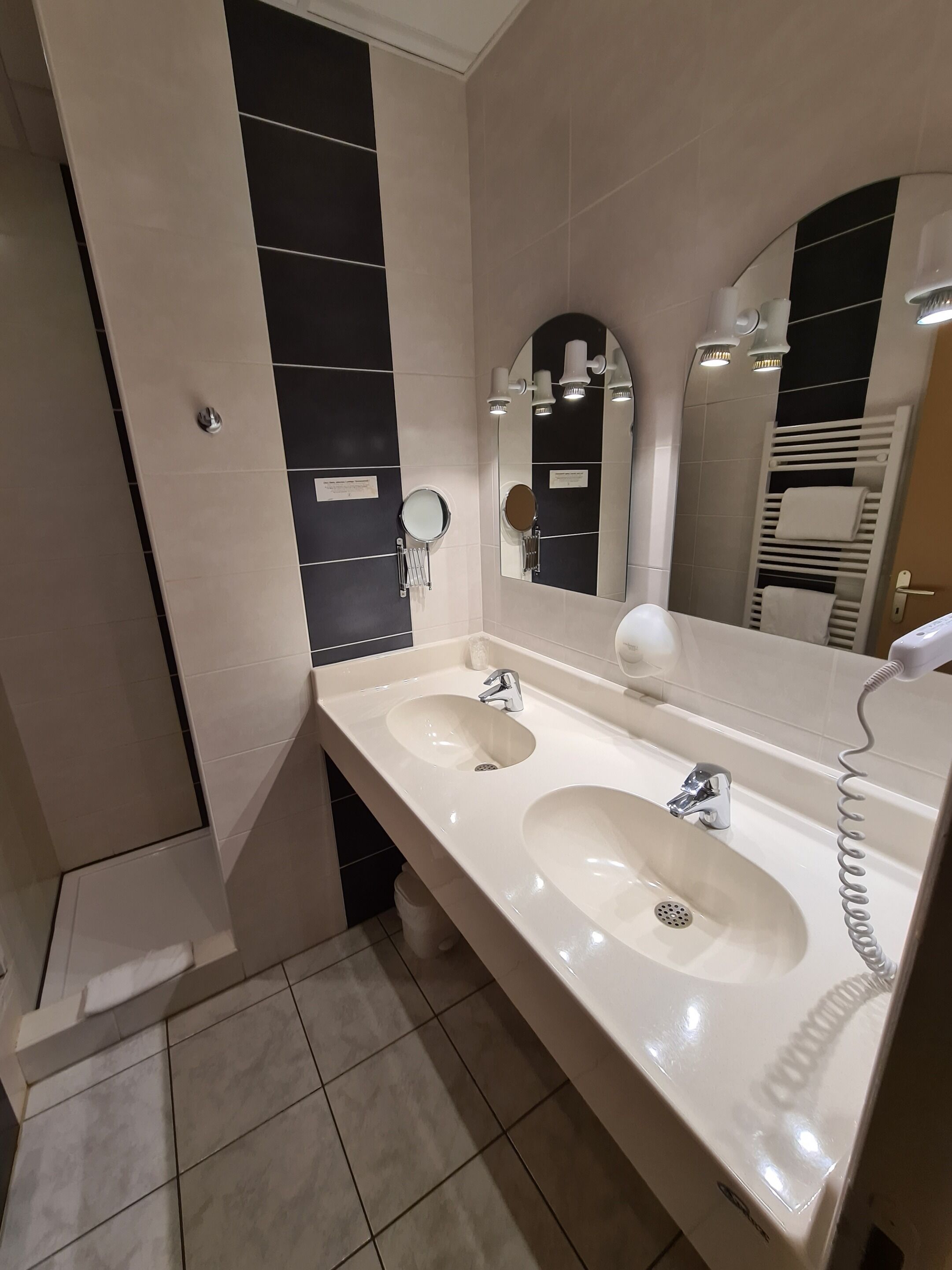 Un baño moderno con dos lavamanos, un espejo grande y un perchero para toallas.