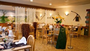 Un restaurante con mesas y sillas de madera, un jarrón decorativo con flores y un barril de madera como pieza central.