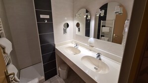 Un baño moderno con dos lavamanos, un espejo grande y un perchero para toallas.