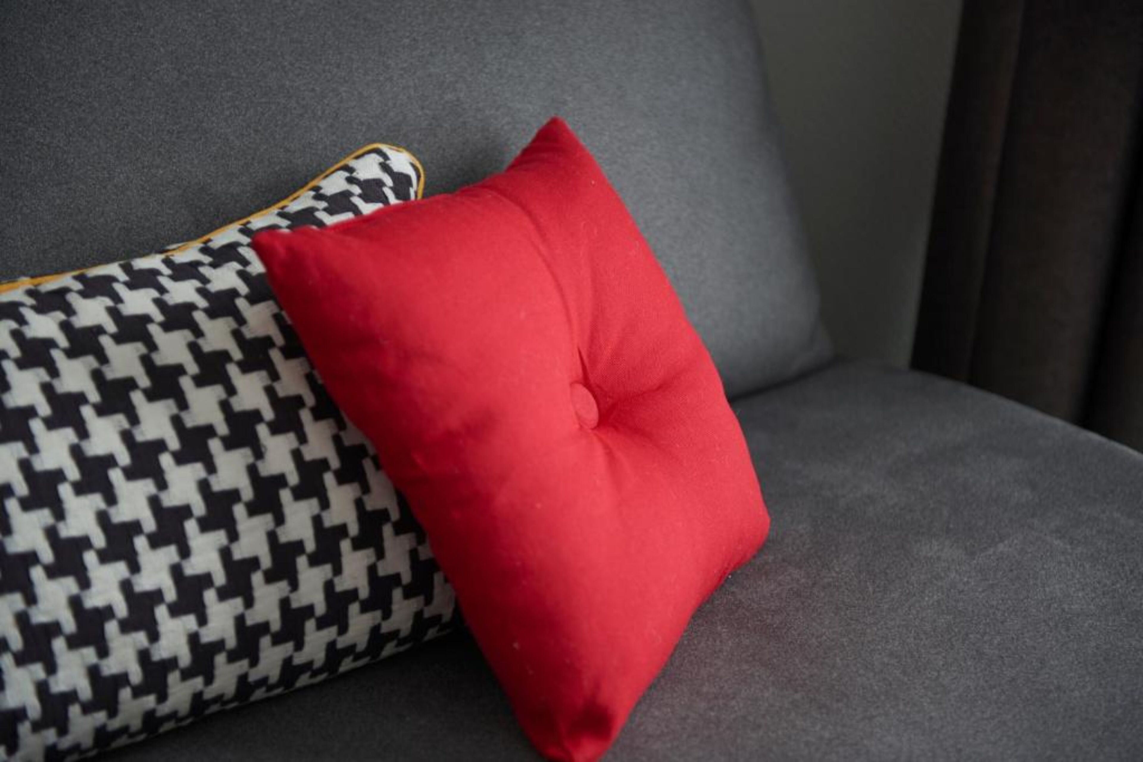 Un canapé gris avec un coussin à motifs rouges et noirs.