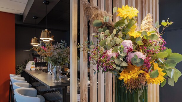 A modern bar area with a wooden partition, a long counter, and a seating arrangement with white chairs. - The Originals Boutique, Hôtel Le Pariou (Issoire)