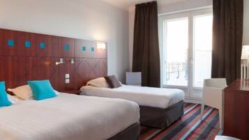 A hotel room with two beds, a wooden headboard, a window with curtains, and a striped carpet.