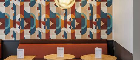 A restaurant interior with a patterned wall, a central light fixture, and seating with 'CARTE BAR' signs.