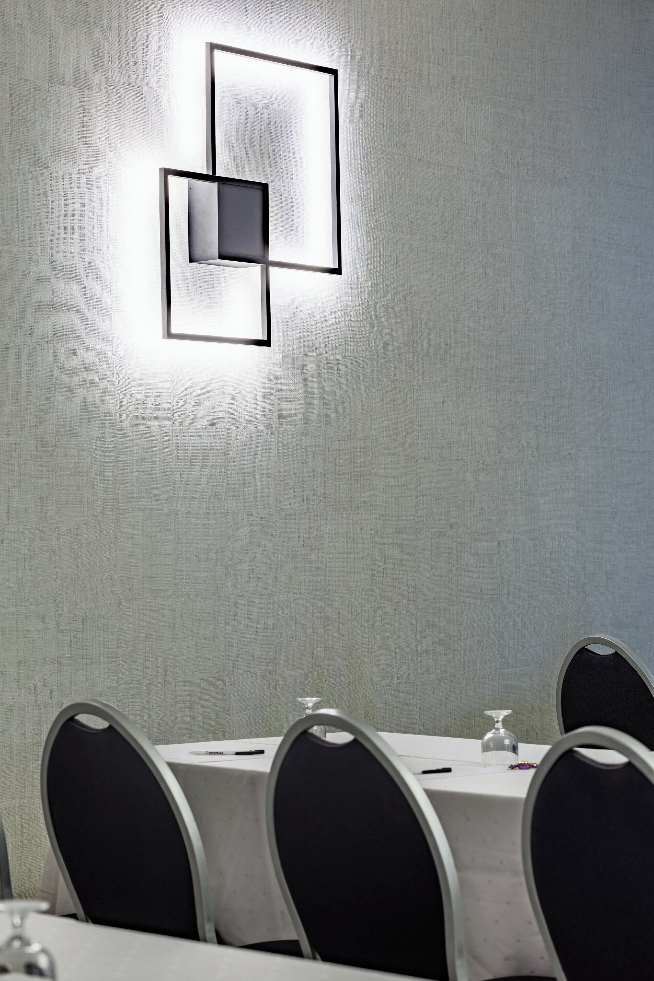 A conference room with a modern light fixture, a white tablecloth, and black chairs.